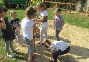 dzieci bawią się wagą w piaskownicy w ogrodzie